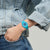 Damenuhr am Handgelenk mit türkisfarbenem Armband und blauem Farbverlauf-Zifferblatt