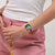 Damenuhr am Handgelenk mit blau-gelbem Zifferblatt und pinkem Armband