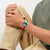 Damenuhr am Handgelenk mit blauem Zifferblatt, gelbem Armband und pinken Akzenten