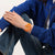 Swatch Armbanduhr am Handgelenk, orangefarbenes Gehäuse, blaues Strickoutfit
