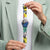Swatch-Armbanduhr am Handgelenk, Stereifenarmband mit Kunstzifferblatt und buntem Design.