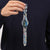 Armbanduhr am Handgelenk mit blau-schwarzem Spritzdekor und orange Zeigern