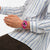 Fuchsia Armbanduhr am Handgelenk auf blau-weiß gestreiftem Hemd