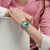Swatch-Chronographenuhr am Handgelenk, pinkes Silikonband und buntes Zifferblatt.