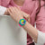 Bunte Swatch-Chronographenuhr am Handgelenk mit pinkem Band und türkis-grünem Gehäuse.