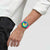 Swatch-Uhr am Handgelenk mit pinkem Silikonarmband und farbiger Tachymeteranzeige.