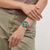 Handgelenk mit rotem Silikonarmband und grüner Chronographenarmbanduhr