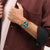 Arm mit rotem Silikonarmband und grüner Chronographenarmbanduhr, Detail auf das Zifferblatt