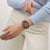 Armbanduhr in Seitenlage am Handgelenk: rotes Armband, dunkles Gehäuse, Chrono-Subziffern