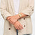Damenuhr am Handgelenk mit rosafarbenem Lederarmband und rundem goldfarbenem Gehäuse