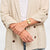 Damenuhr am Handgelenk mit rosafarbenem Lederarmband und rundem goldfarbenem Gehäuse