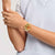 Swatch-Armbanduhr am Handgelenk: rundes goldfarbenes Zifferblatt, weißes Armband mit rotem Muster