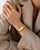 Goldfarbene Armbanduhr mit rechteckigem Ziffernblatt und römischen Ziffern, Metallgliederarmband