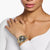 Damen-Armbanduhr am Handgelenk mit schwarzem Zifferblatt und goldfarbenem Metallband