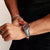 Armbanduhr am Handgelenk mit dunkelrotem Zifferblatt und silbernem Metallarmband