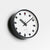 Rundliche Wanduhr mit weißem Zifferblatt, schwarzem Gehäuse und roten Details am Zifferblatt
