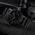 Herrenarmbanduhr von Luminox seitlich im Detail, grün leuchtende Punkte auf schwarzem Zifferblatt