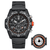 Montre bracelet pour homme avec cadran noir et bordure orange, à côté d'un instrument de mesure rond