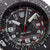 Gros plan : cadran de montre pour homme noir avec index lumineux, grands chiffres et lunette rouge
