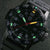 Montre pour homme : Gros plan sur un cadran noir avec des index verts lumineux et la date