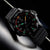 Montre de sport sous un angle semblable à celui du poignet : boîtier noir, anneau de lunette rouge, index luminescents verts