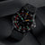 Montre de sport avec bracelet noir, cadran noir et lunette rouge ; date visible à 3 heures