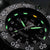 Gros plan d'une montre pour homme : cadran noir avec index luminescents verts et date