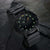 Montre noire pour homme avec index, lunette et bracelet en caoutchouc verts lumineux