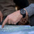 Montre homme au poignet avec bracelet en caoutchouc noir et aiguilles lumineuses