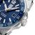 Montre bracelet avec cadran bleu, lunette moletée et couronne sur le côté.