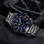 Montre bracelet en gros plan avec cadran bleu, index lumineux et affichage de la date.