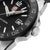 Gros plan : montre de plongée avec lunette noire, aiguilles lumineuses et couronne vissée