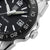 Montre homme en détail : cadran noir, lunette argentée et couronne à 3h