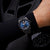 Montre pour homme au poignet avec cadran bleu, boîtier sombre et bracelet en silicone