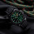 Montre homme avec bracelet en caoutchouc noir et cadran vert, aiguilles lumineuses visibles