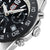 Détail de la montre homme sur le côté : lunette noire, couronne et boîtier avec des index.