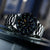 Montre bracelet pour homme avec cadran noir, aiguilles lumineuses et lunette en acier inoxydable en détail