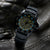 Montre bracelet pour homme portée en biais : boîtier noir, cadran beige, bracelet en caoutchouc