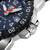 Gros plan du bord du boîtier : fond en acier inoxydable, zone de chronographe moletée et aspect cadran bleu foncé.
