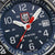 Gros plan du cadran : index blancs, pointe rouge de l'aiguille des secondes, logo LUMINOX et guichet de date.