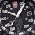 Detailaufnahme der Herrenarmbanduhr: schwarzes Zifferblatt, Leuchtzeiger und Datum bei 3