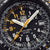 Vue détaillée de la montre pour homme : aiguilles et chiffres luminescents sur cadran noir.