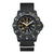 Montre homme avec boîtier noir, bracelet textile noir et chiffres luminescents sur cadran sombre.