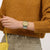 Swatch Herrenuhr am Handgelenk, goldenes Zifferblatt mit Indexen und zweifarbiges Band