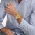 Swatch Herrenuhr am Arm, goldenes Zifferblatt und zweifarbiges Metallband