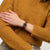 Armbanduhr am Handgelenk mit dunkelviolettem Zifferblatt und burgundfarbenem Band