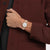 Damenuhr am Handgelenk mit roségoldfarbenem Metallarmband und weißem Zifferblatt