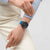 Herren-Chronographenuhr am Handgelenk zu beigem Pullover, blaues Textilarmband