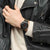 Swatch Chronographen-Uhr am Handgelenk mit schwarzem Gehäuse und khakifarbenem Textilband