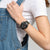 Armbanduhr mit schwarzem Chronographen-Zifferblatt und khakifarbenem Textilarmband am Handgelenk